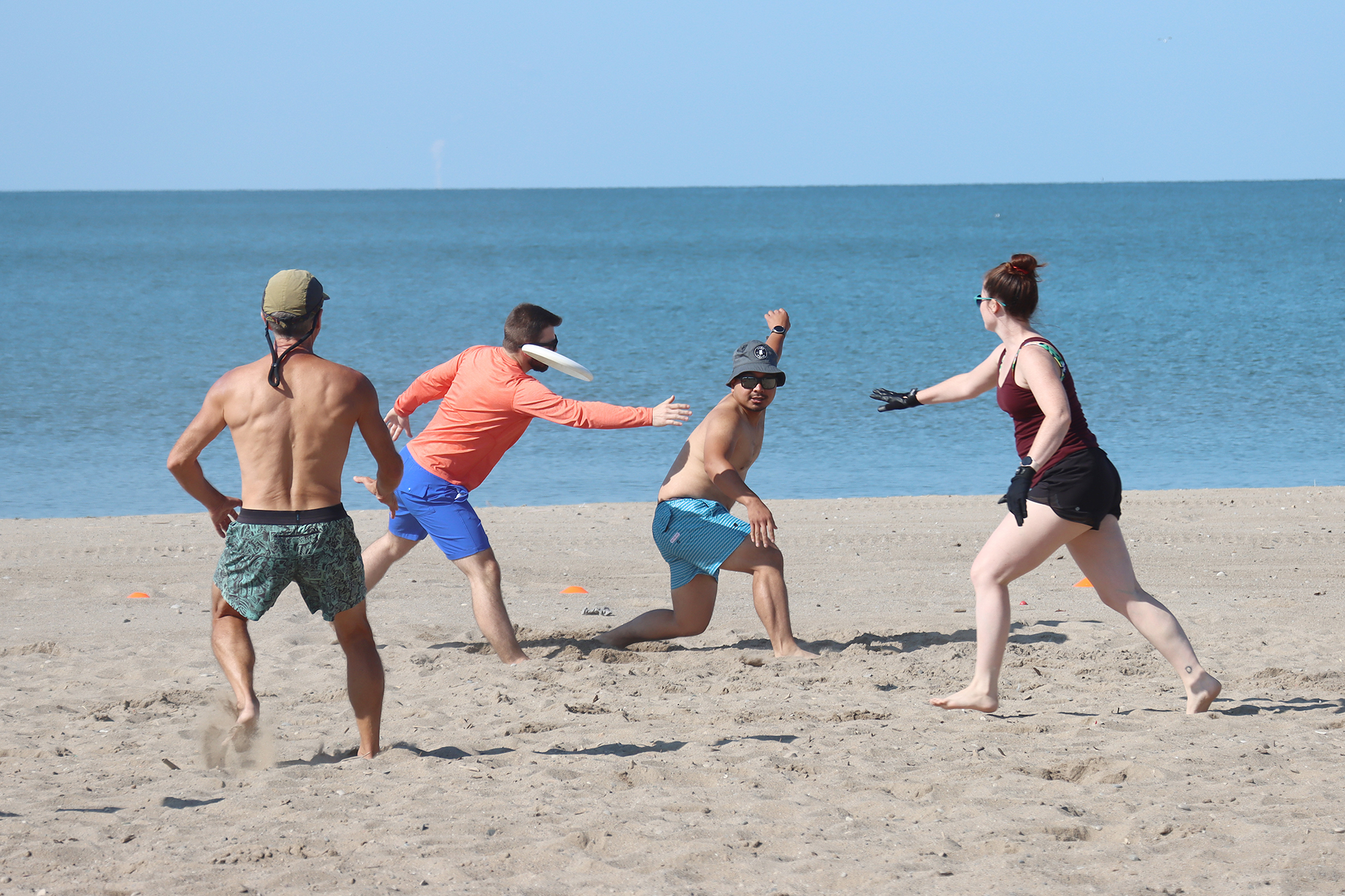 Players of the new "Ultimate" frisbee game playing on the beach.