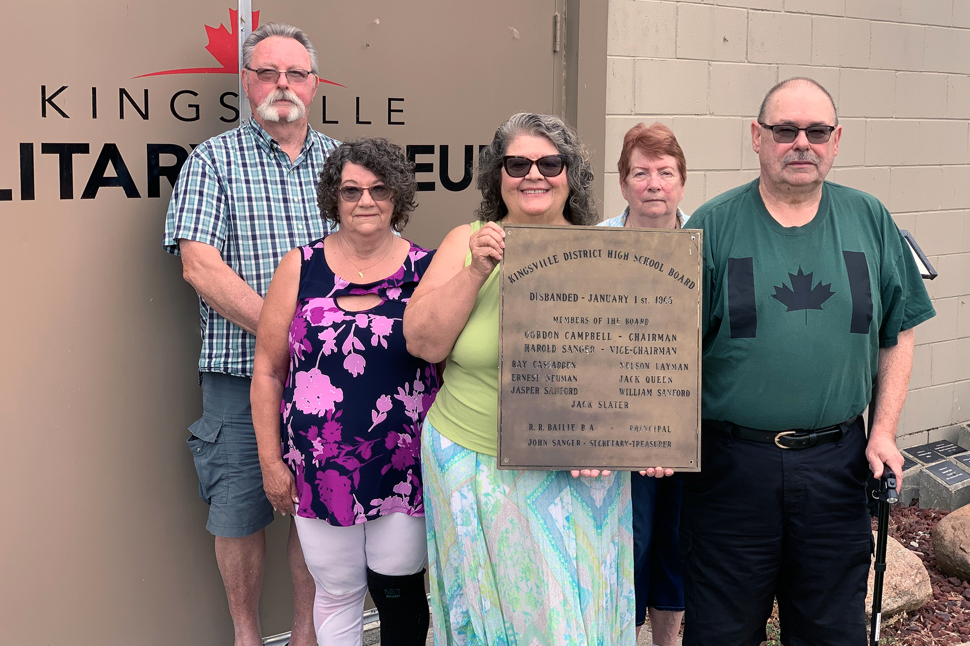 Group of individuals outside holding the historical plaque that will be displayed in the museum.