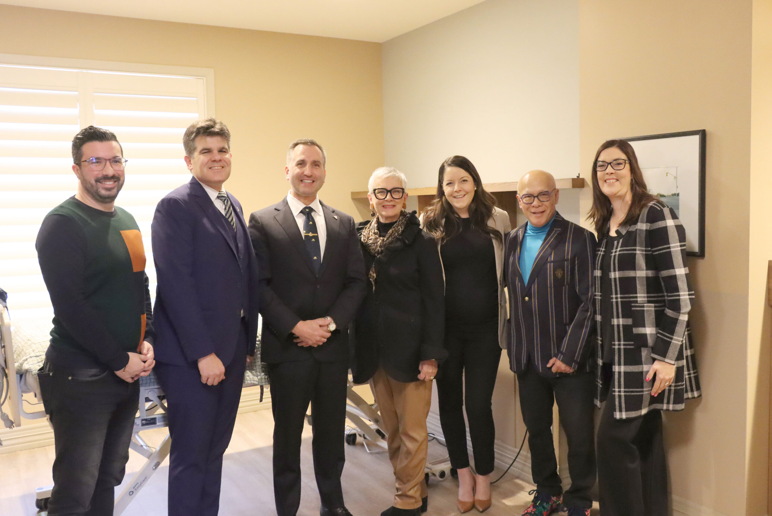 A group of people standing in the new hospice room. From left to right are Erie Shores Health Foundation Director Carmelo DiGrandi, MPP Windsor-Tecumseh Andrew Dowie, MPP Chatham-Kent Leamington Trevor Jones, Leamington Mayor and Warden of Essex County Hilda MacDonald, Hospice of Windsor-Essex Executive Director Katharen Bortolin, Hospice of Windsor Essex Chair Dr. Gary Ing and Erie Shores Health Foundation Executive Director Penny Bellhouse.