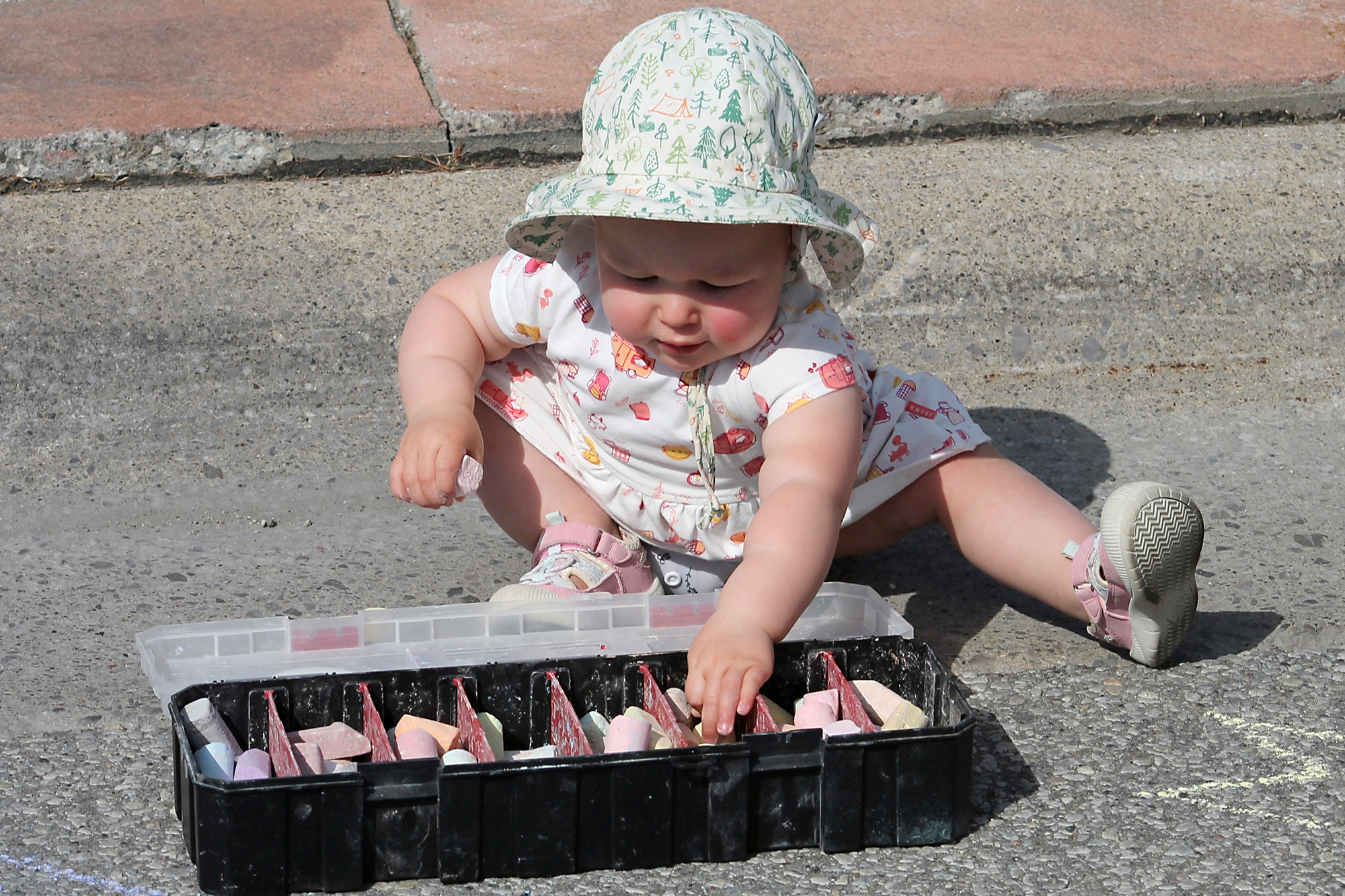 One-year-old McKenna enjoys drawing with chalk in the kids zone at the Cottam Block Party.