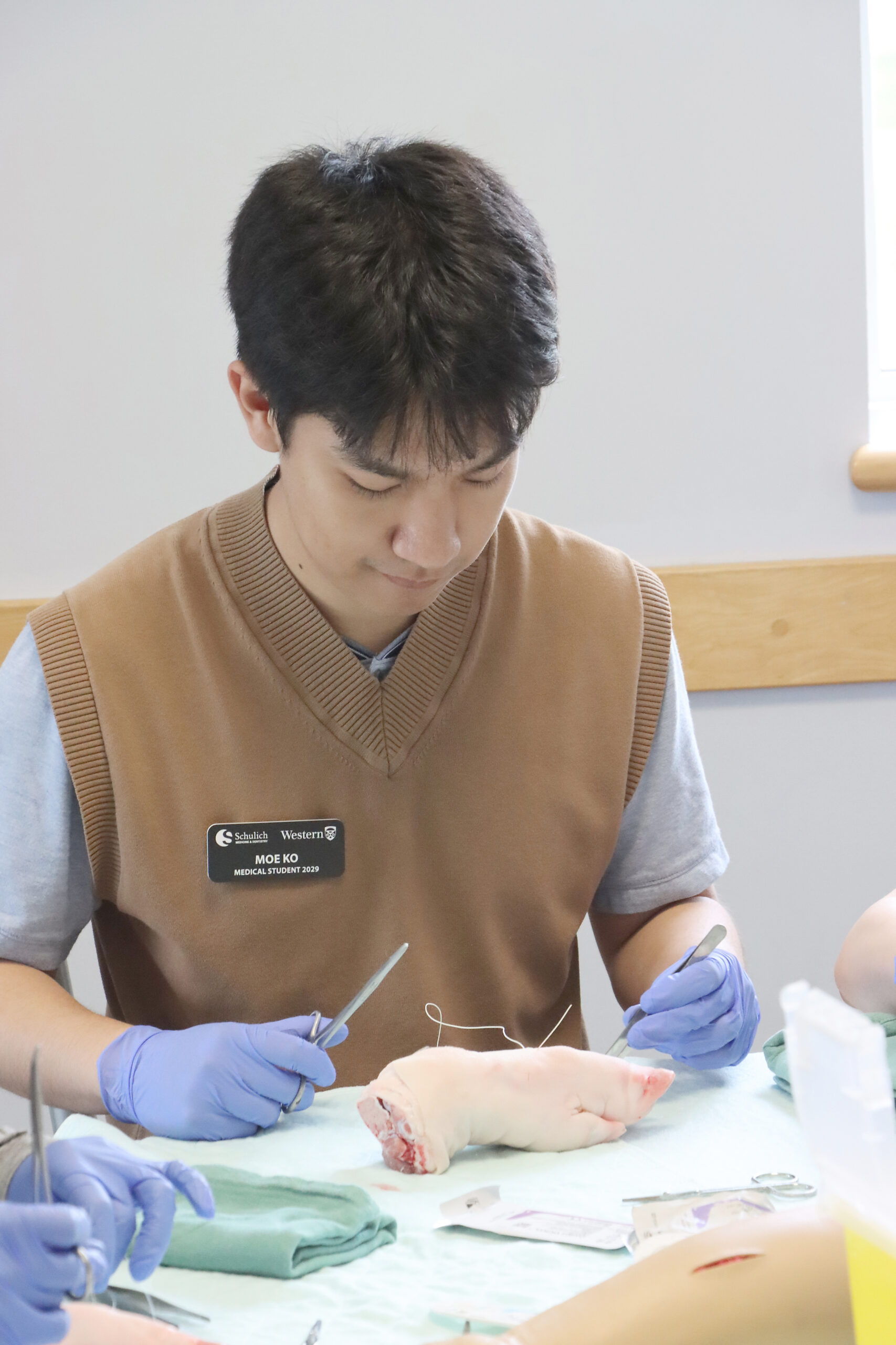 Medical student Moe Ko tries his hand at suturing a pig’s foot during Discovery Week at Erie Shores Health- Care.