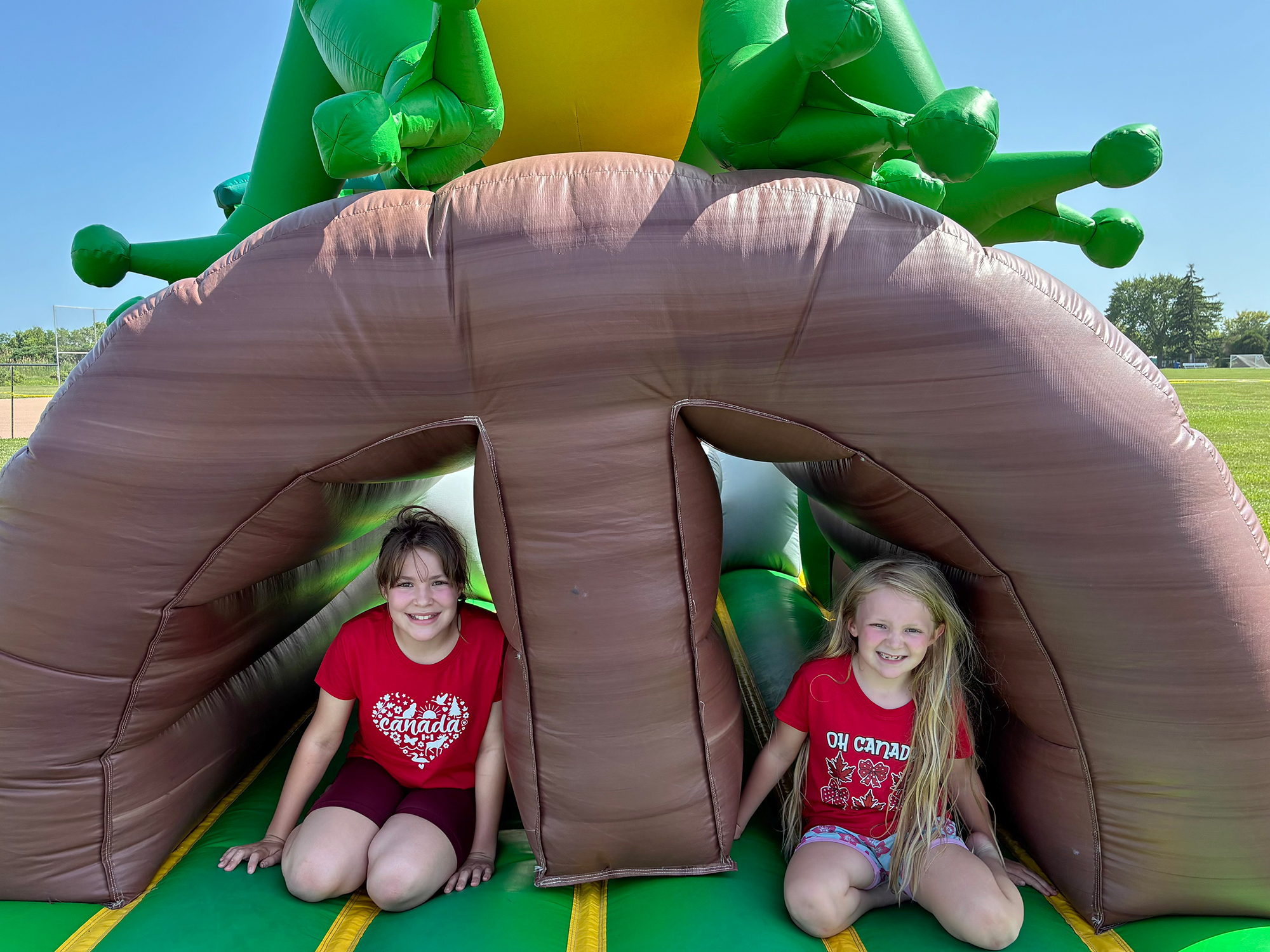Lily and Haley Baltzer take a break near the tropical inflatable obstacle course during the Canada Day celebration in Kingsville.