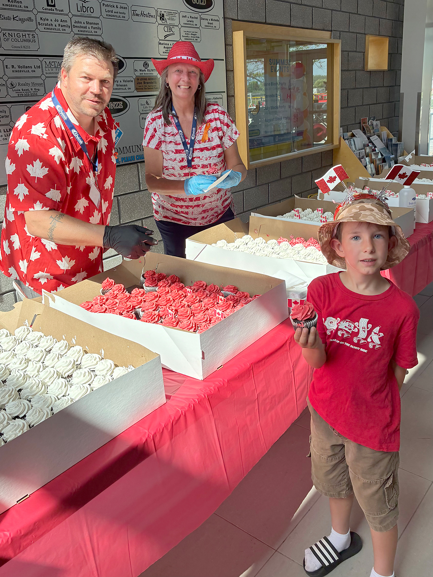 Henry Comartin holds a chocolate cupcake with Thomas Neufeld and Debby Jarvis-Chausse during Canada Day celebrations inside the Kingsville Arena.