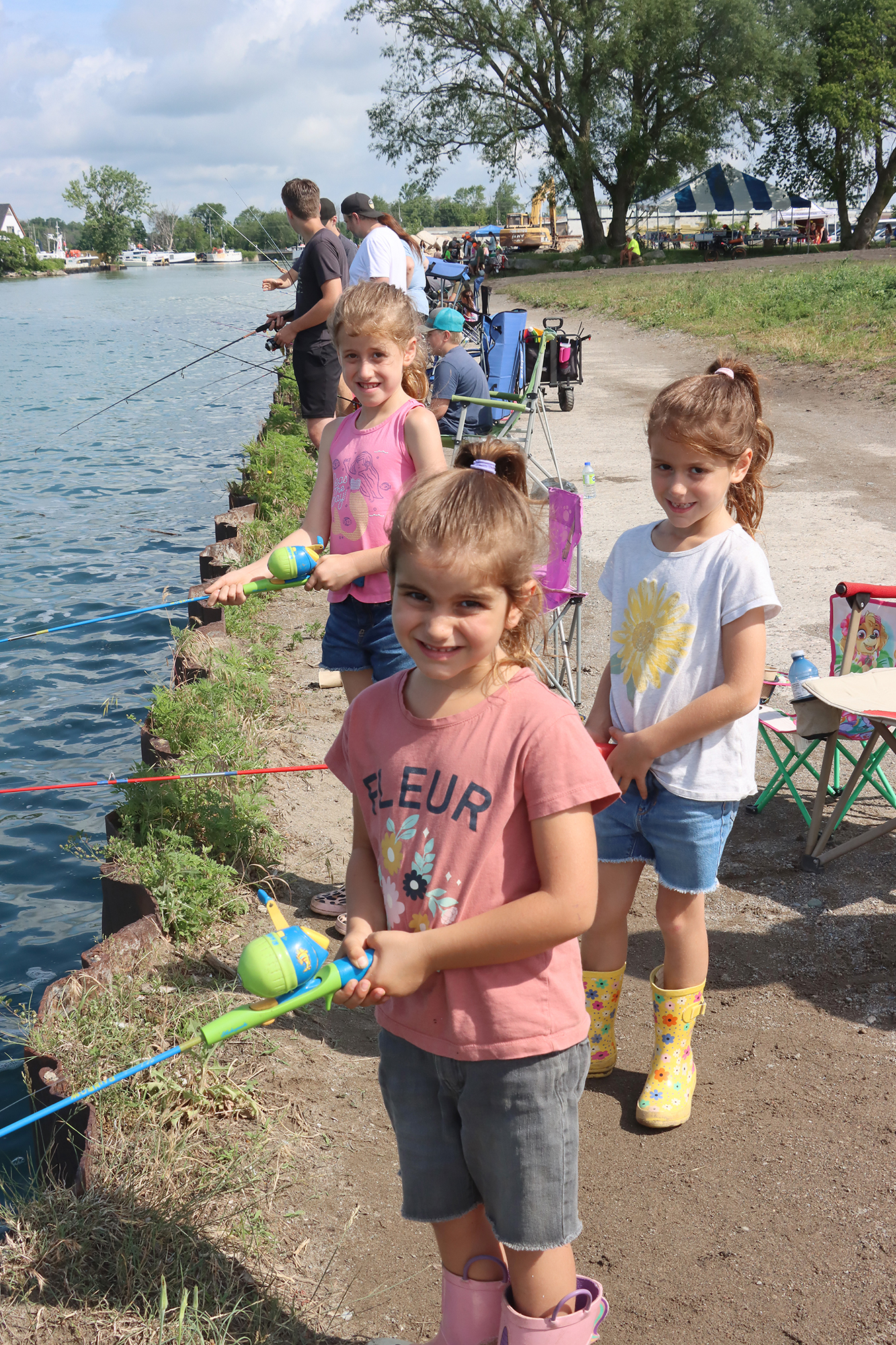 Three sisters—Elisabeth, Aaliyah and Adelaide—wait eagerly with their fishing gear as they take part in the Southwest Outdoors Club Kids Fishing Derby.