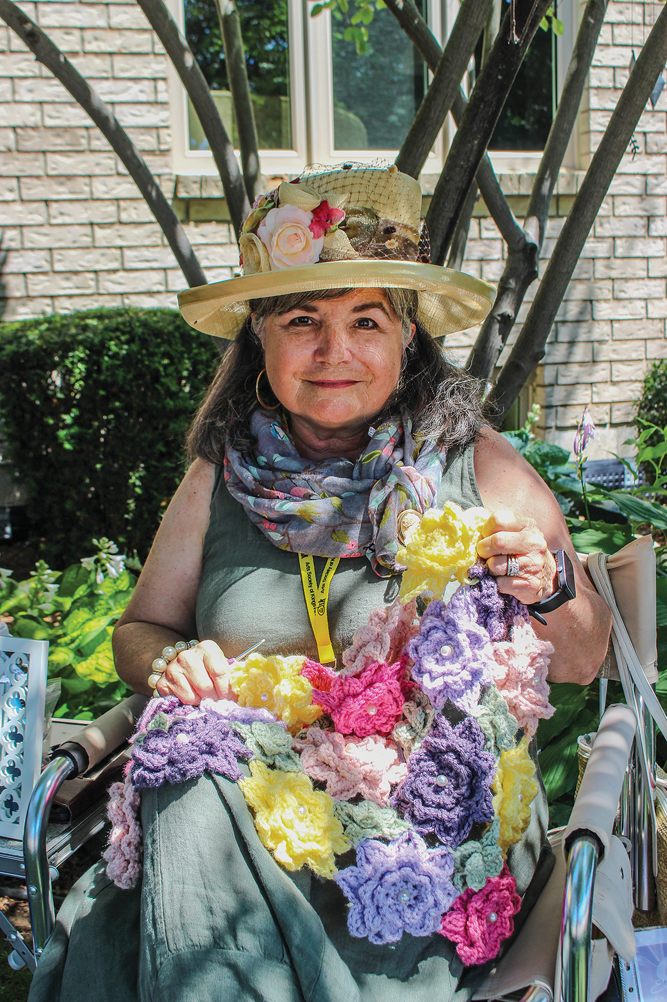 Artist in Residence Michelle Sprout crochets a flower shawl at a featured garden during the Kingsville Garden Tour.