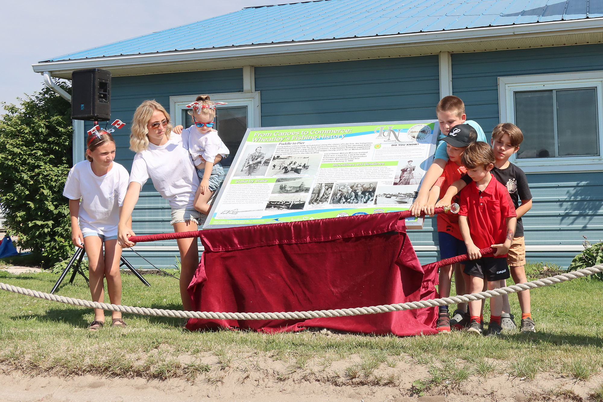 Children from the McLean and Cobby families stand beside the newly unveiled historical plaque commemorating Wheatley's fishing heritage at Wheatley Harbour.