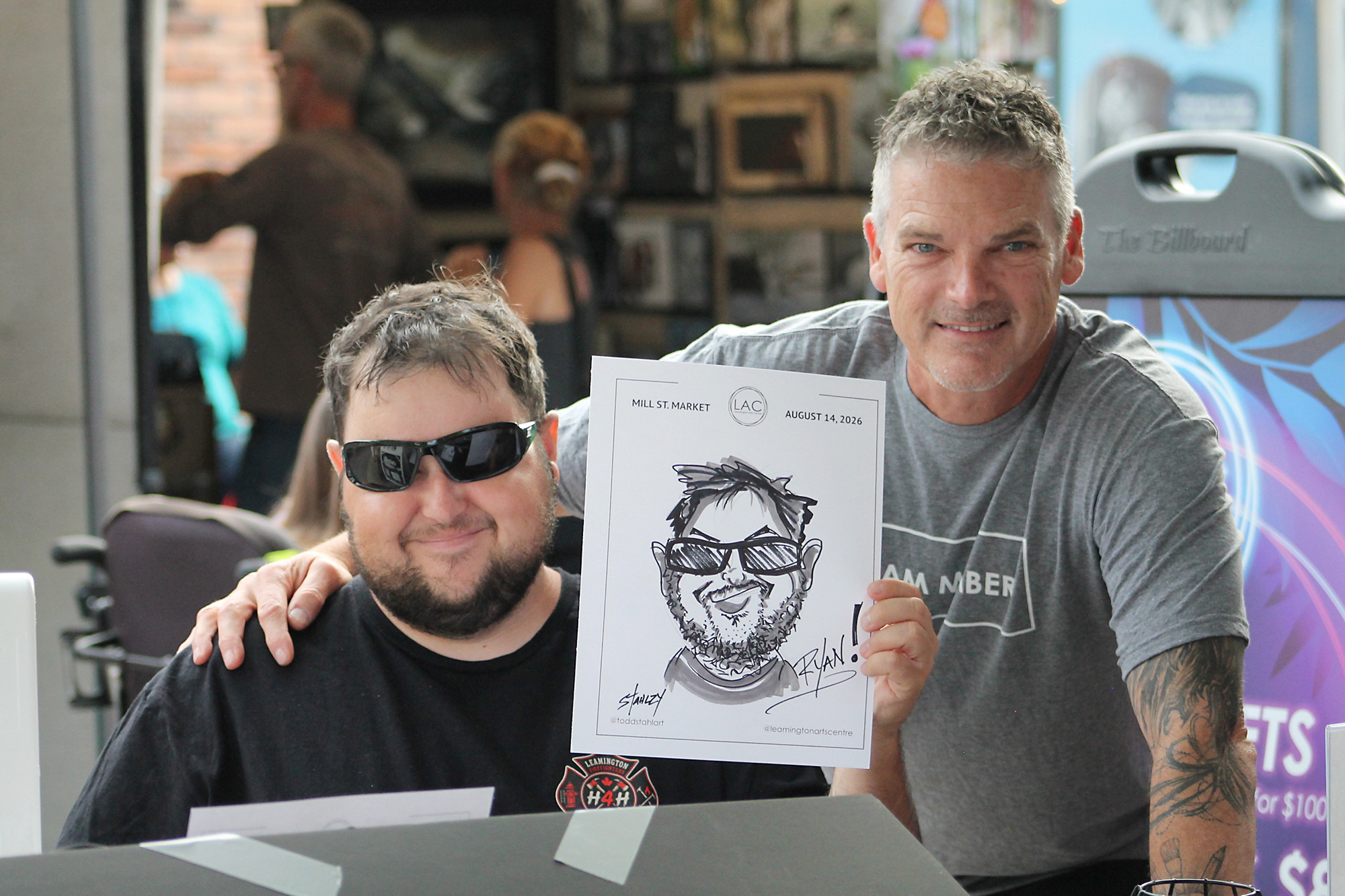 Ryan Issell holds his caricature alongside local artist Todd Stahl at the Mill Street Market in Leamington.