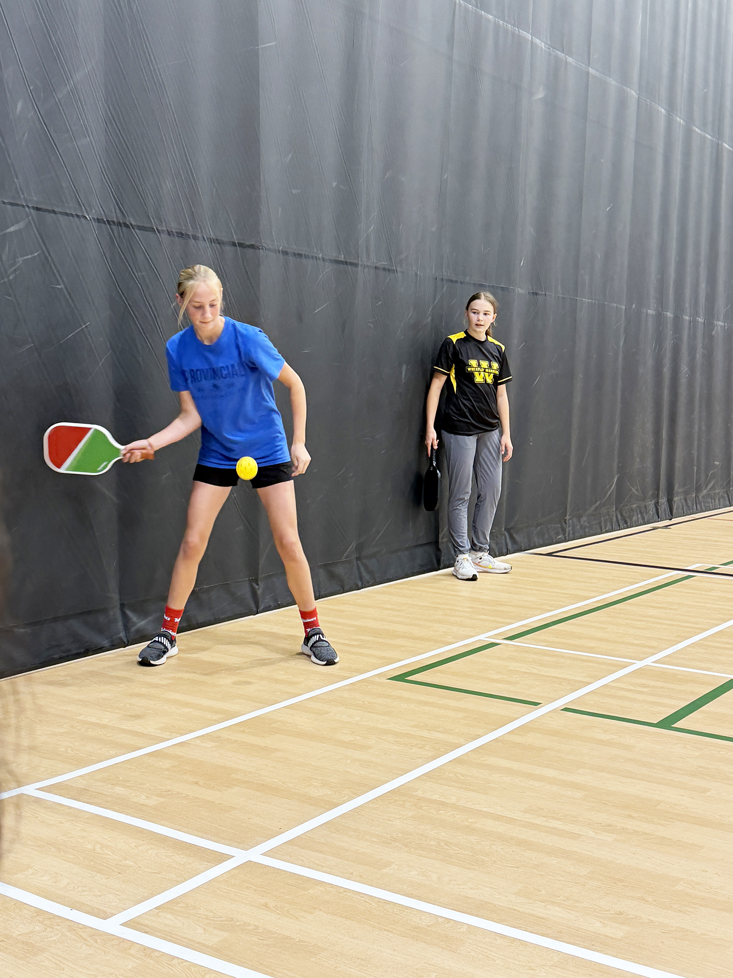 Wheatley student Mila Epplett returns the ball as Bentley Kaiser looks on.
