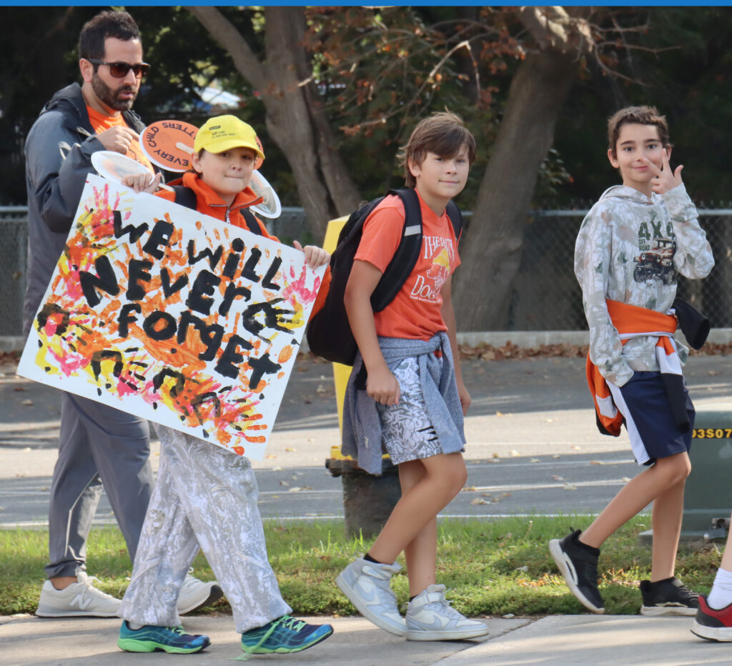 Students and staff from local schools making their way along Erie Street during the Orange Shirt Day walk.